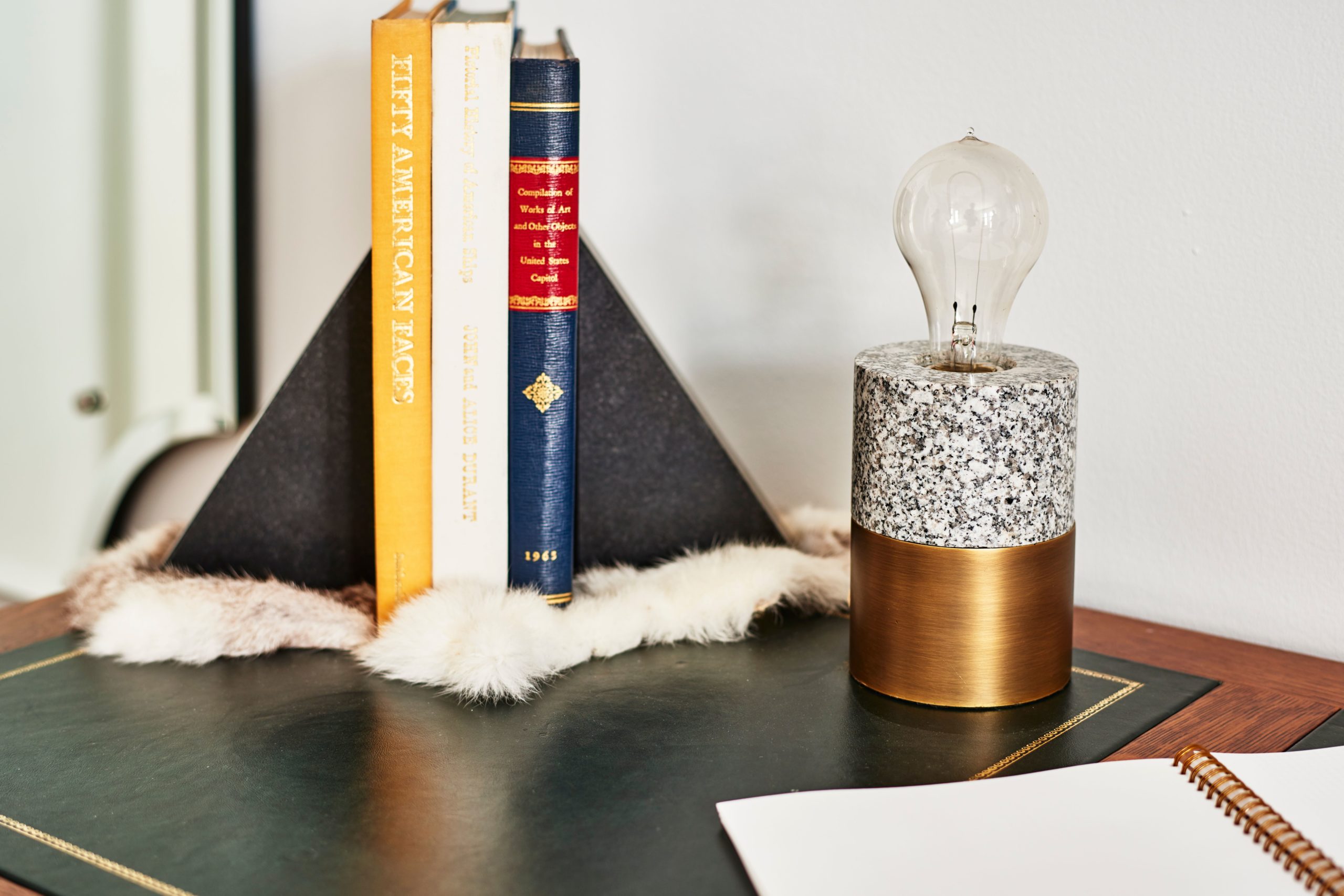 Picture of stand with books and bulb on it with white wall