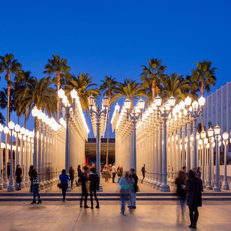 picture of pillars with light and trees with peoples around them