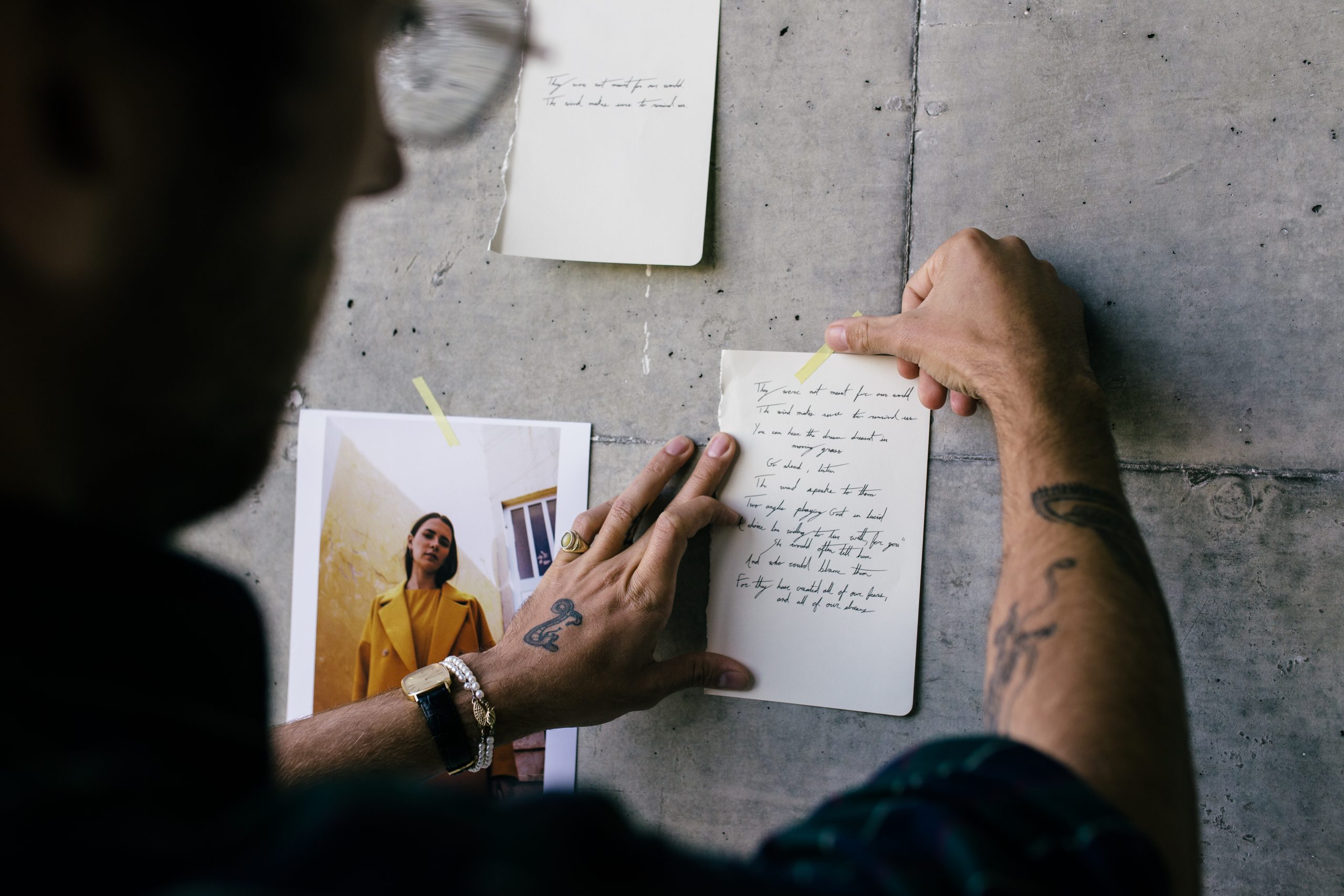 Man wearing specs holding a note of paper with the wall