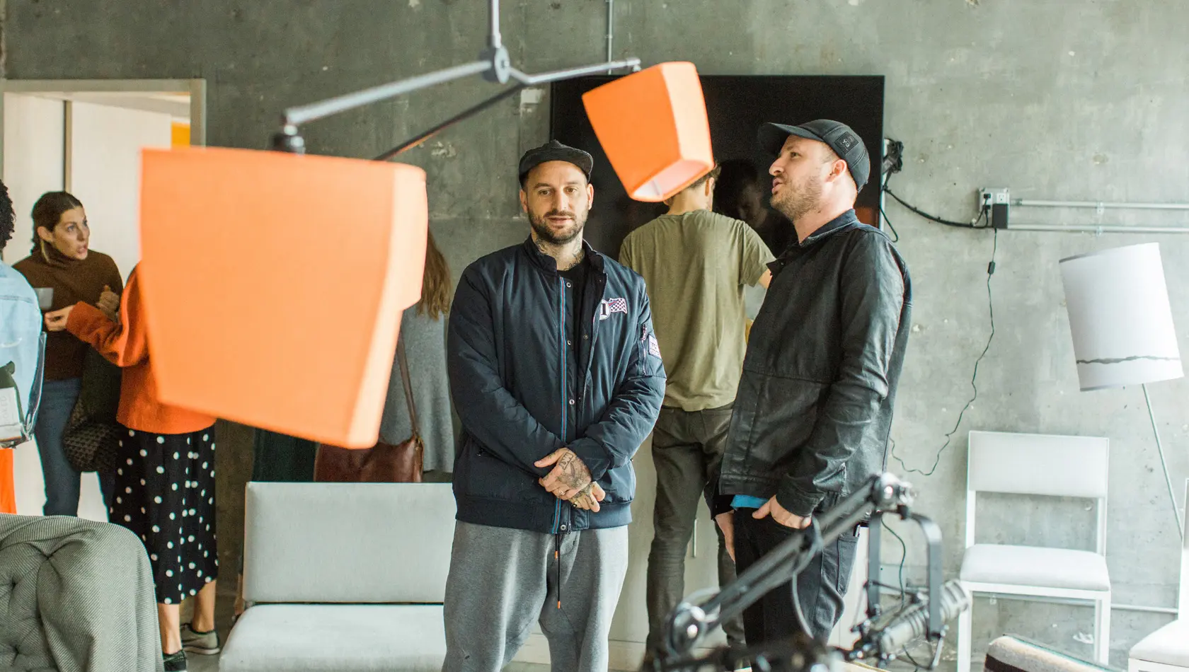 Two man discussing in a with many people standing in the background