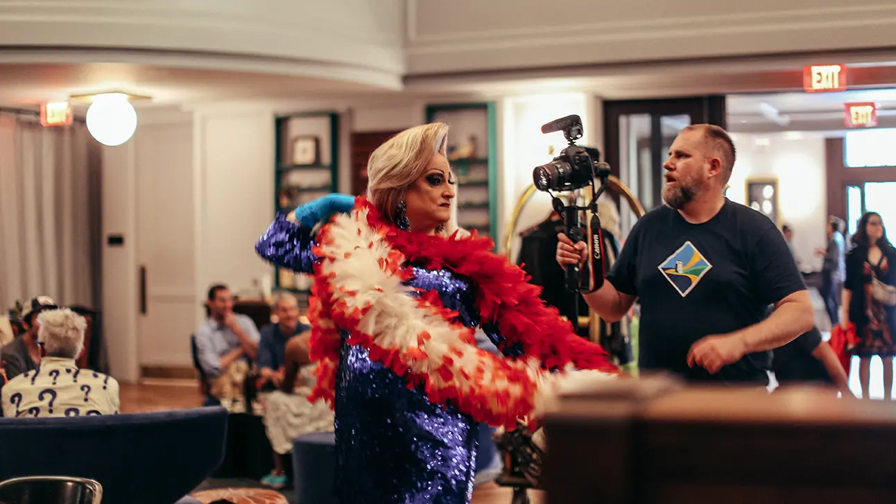 woman wearing blue dress and camera man standing behind him