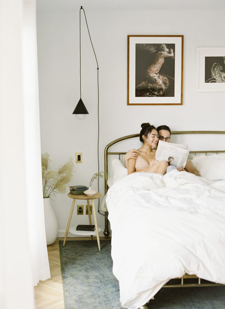 Couple in a hotel bedroom reading newspaper