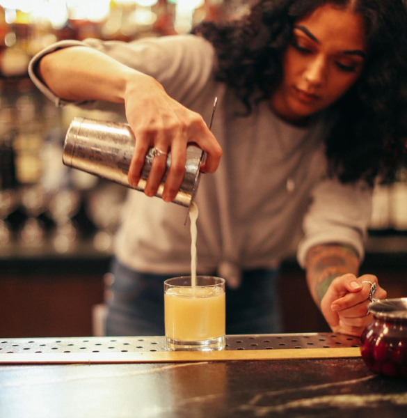 A girl is pouring a drink into a glass.