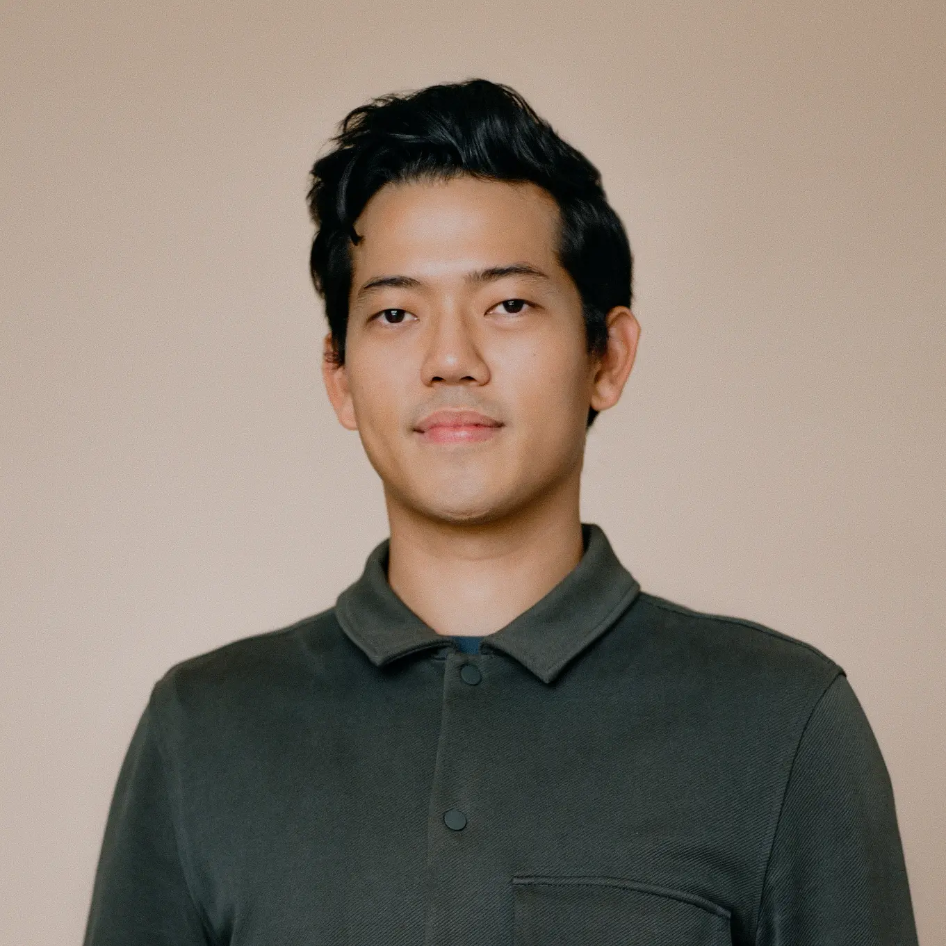 A man in a green tee poses gracefully for a captivating photograph.