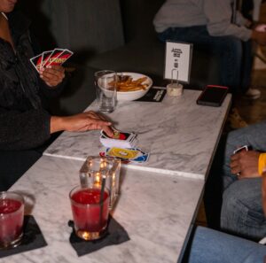 People play Uno on two marble tabletops that also hold cocktails and food.