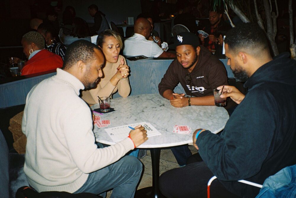 People sit around a table focused on playing cards