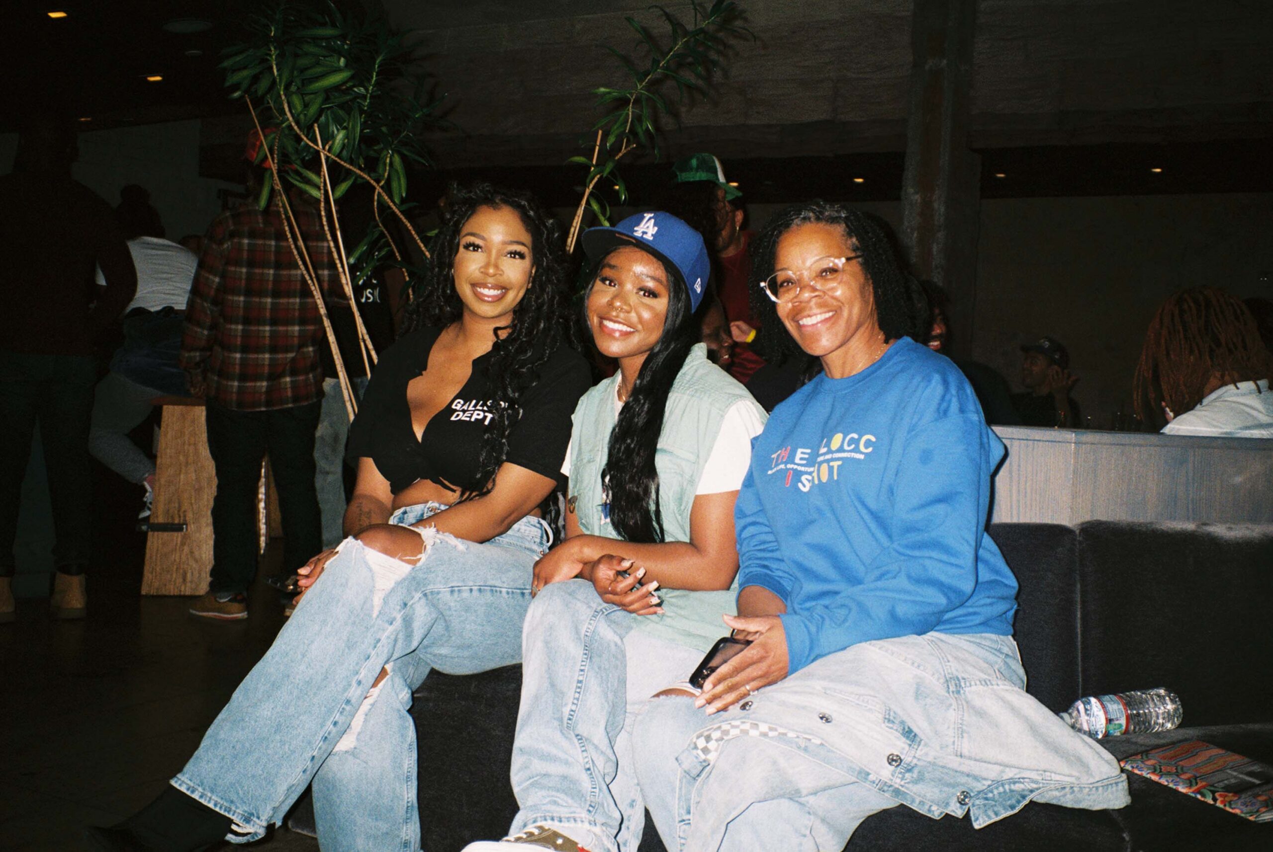 Three women sit side by side and pose