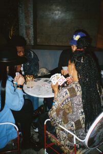 Four people sit around a small table playing cards