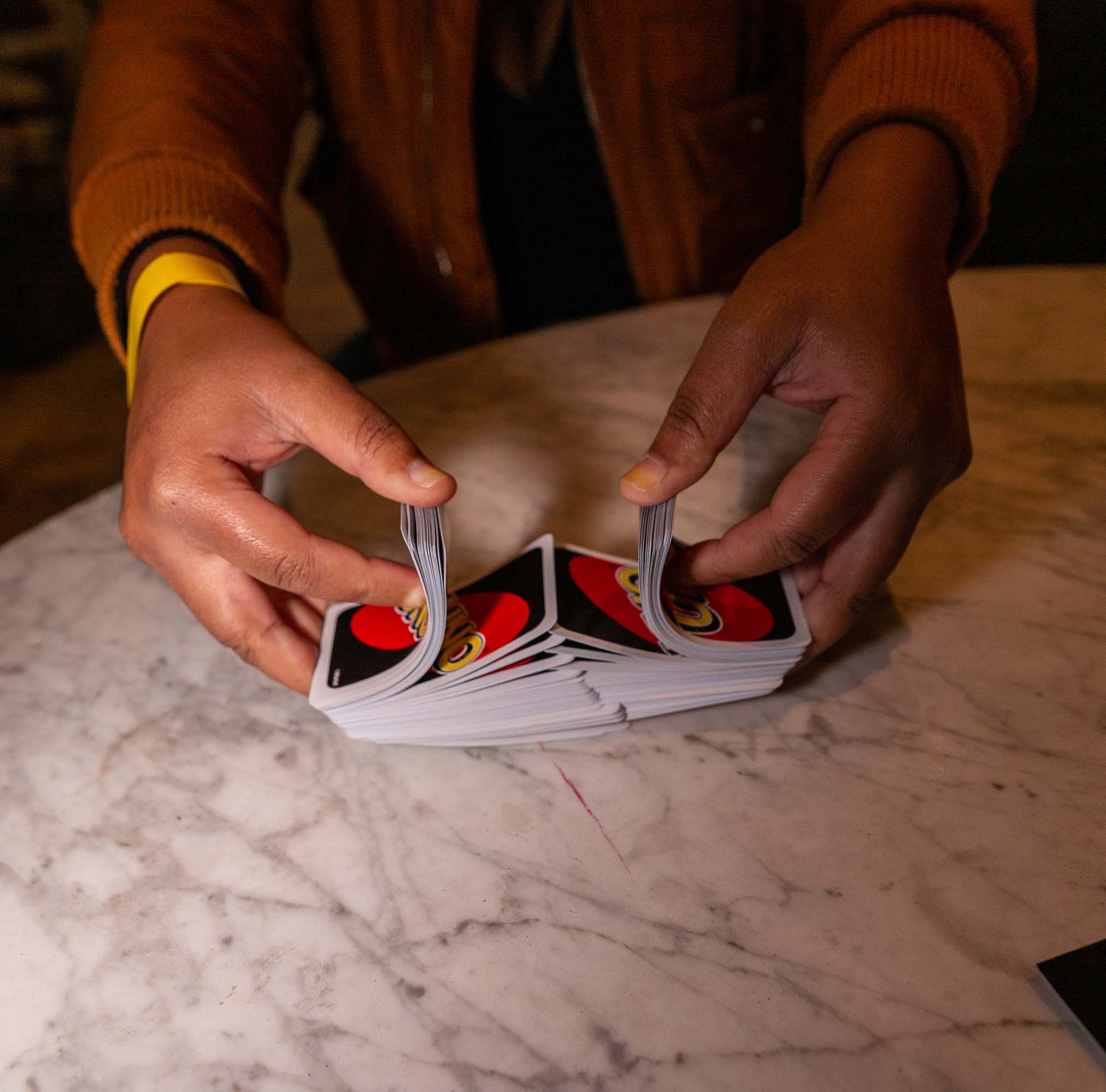 Guy delicately shuffling playing cards with two hands in a mesmerizing motion.