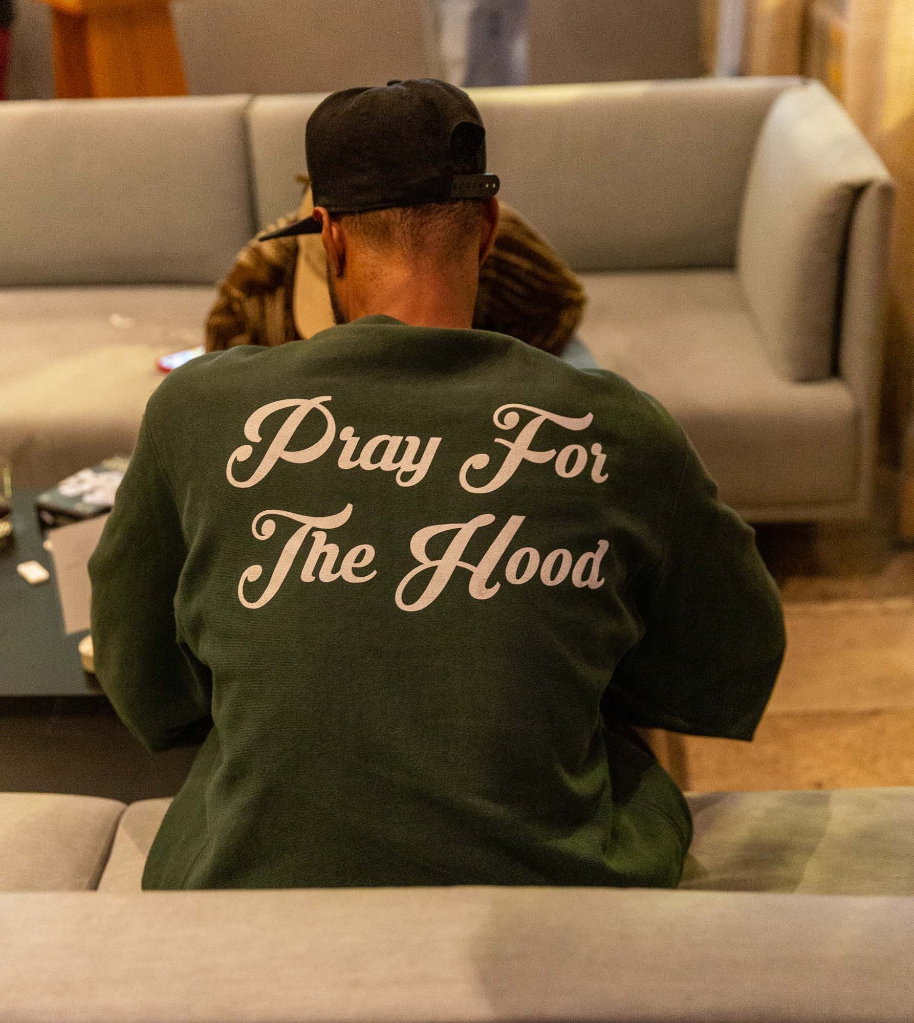 Boy in green tee and black cap lounging comfortably on the sofa.
