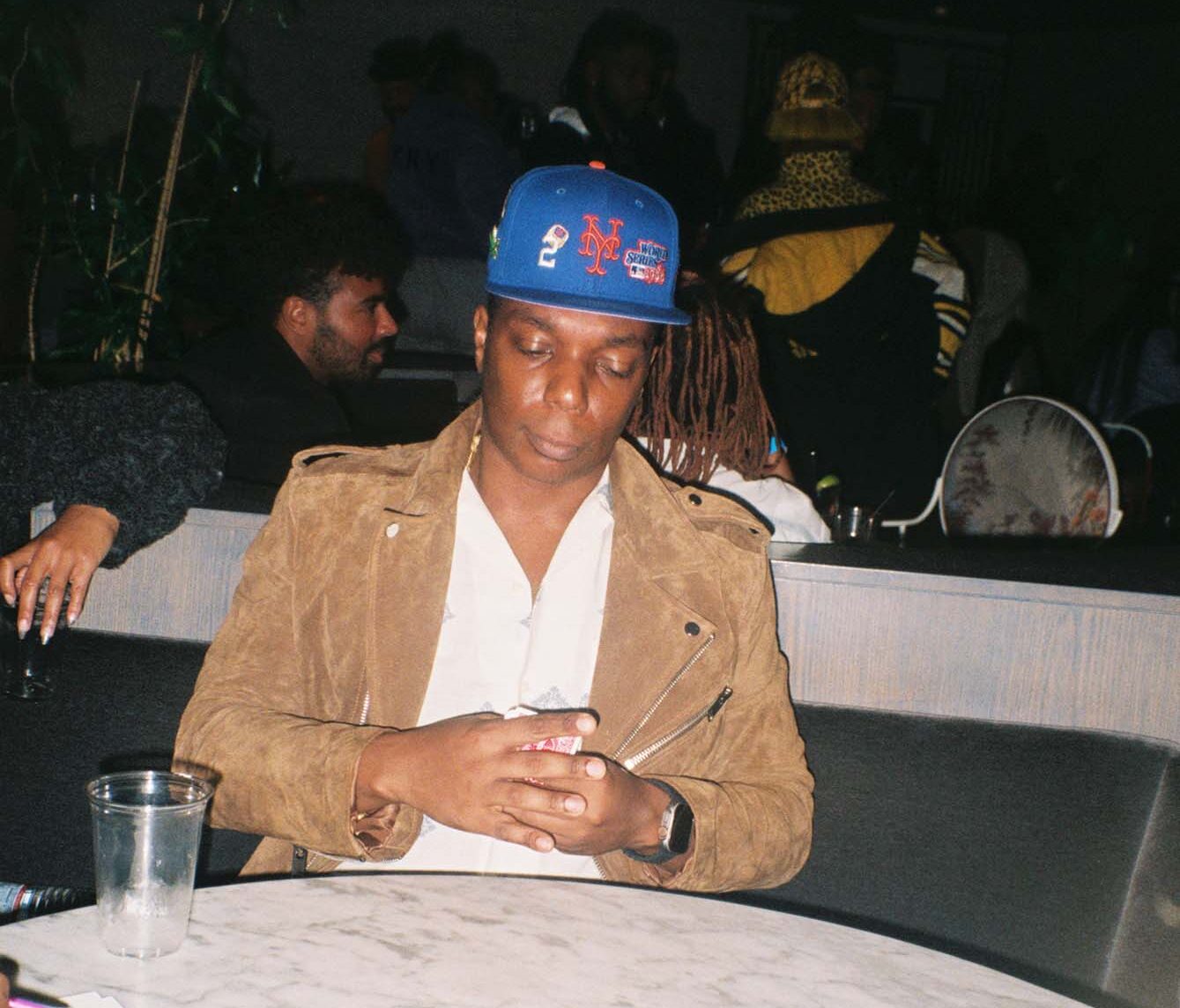 A man sits at a table holding playing cards in his hands