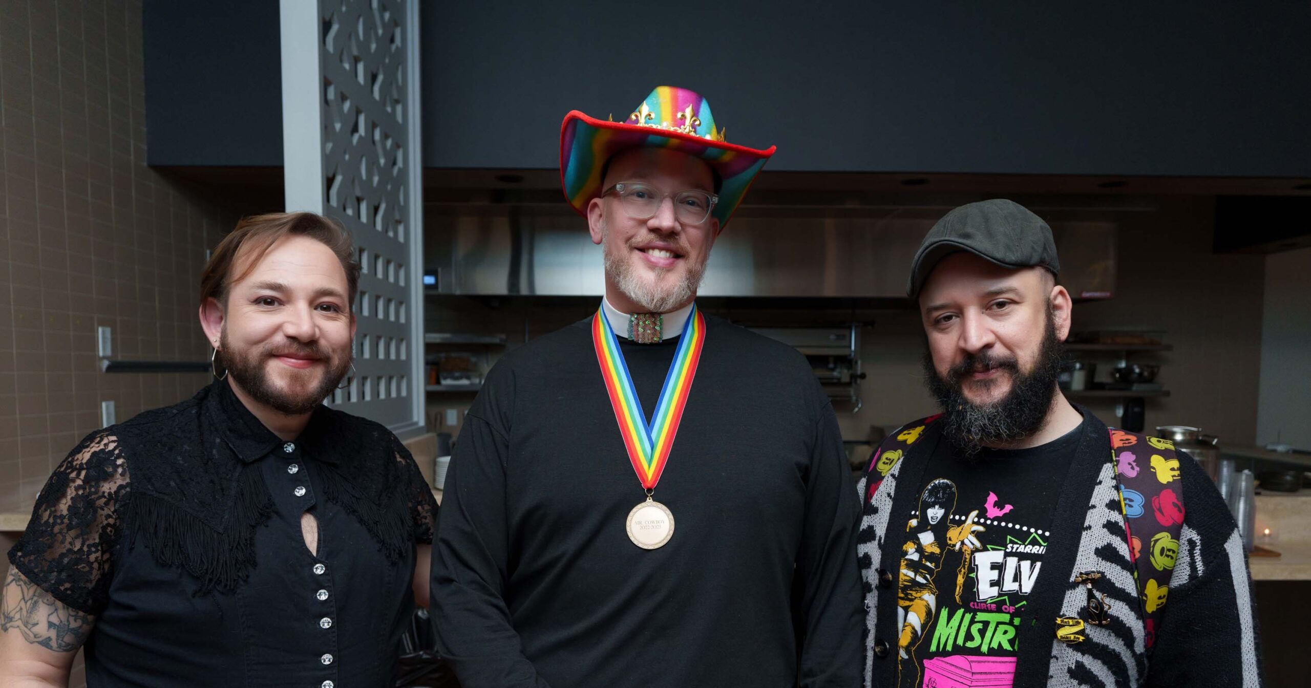 Three men with beards and lively outfits look at the camera