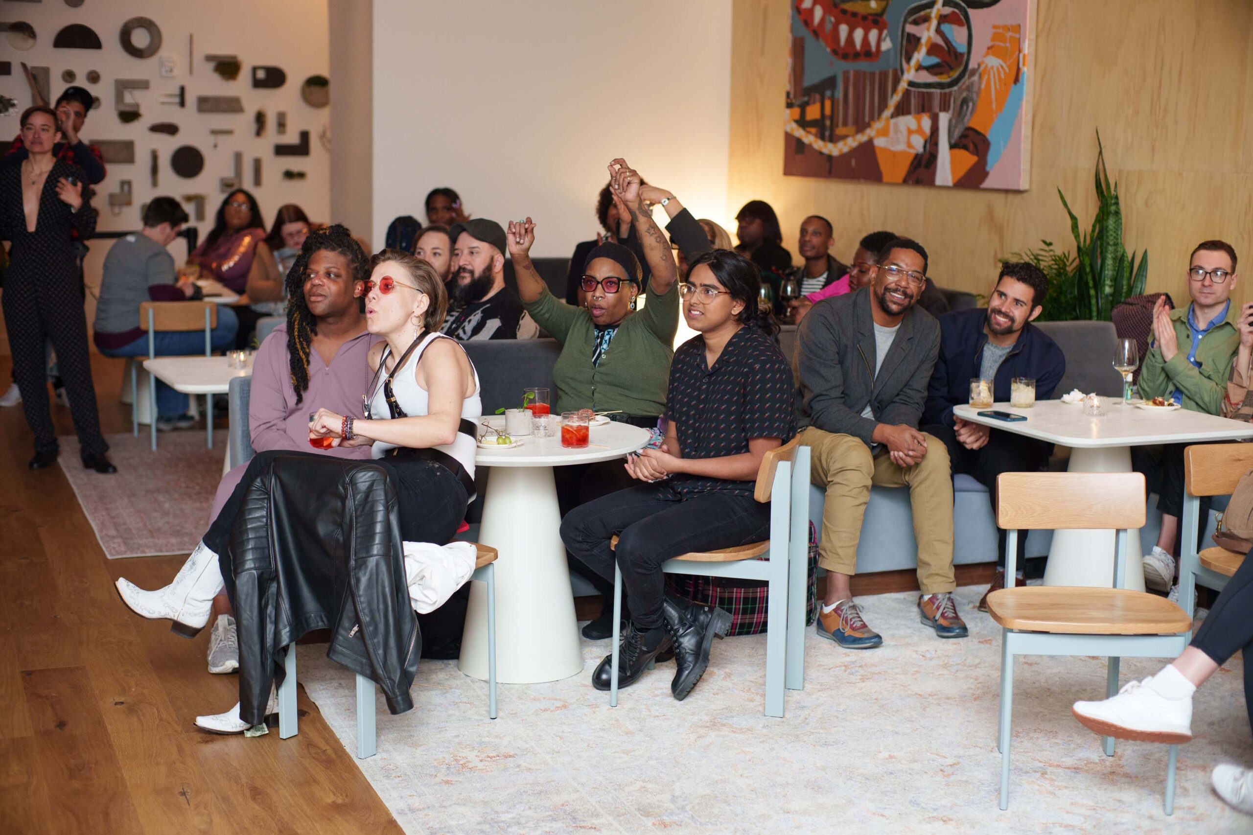 A seated crowd in a hotel lobby watches a performance
