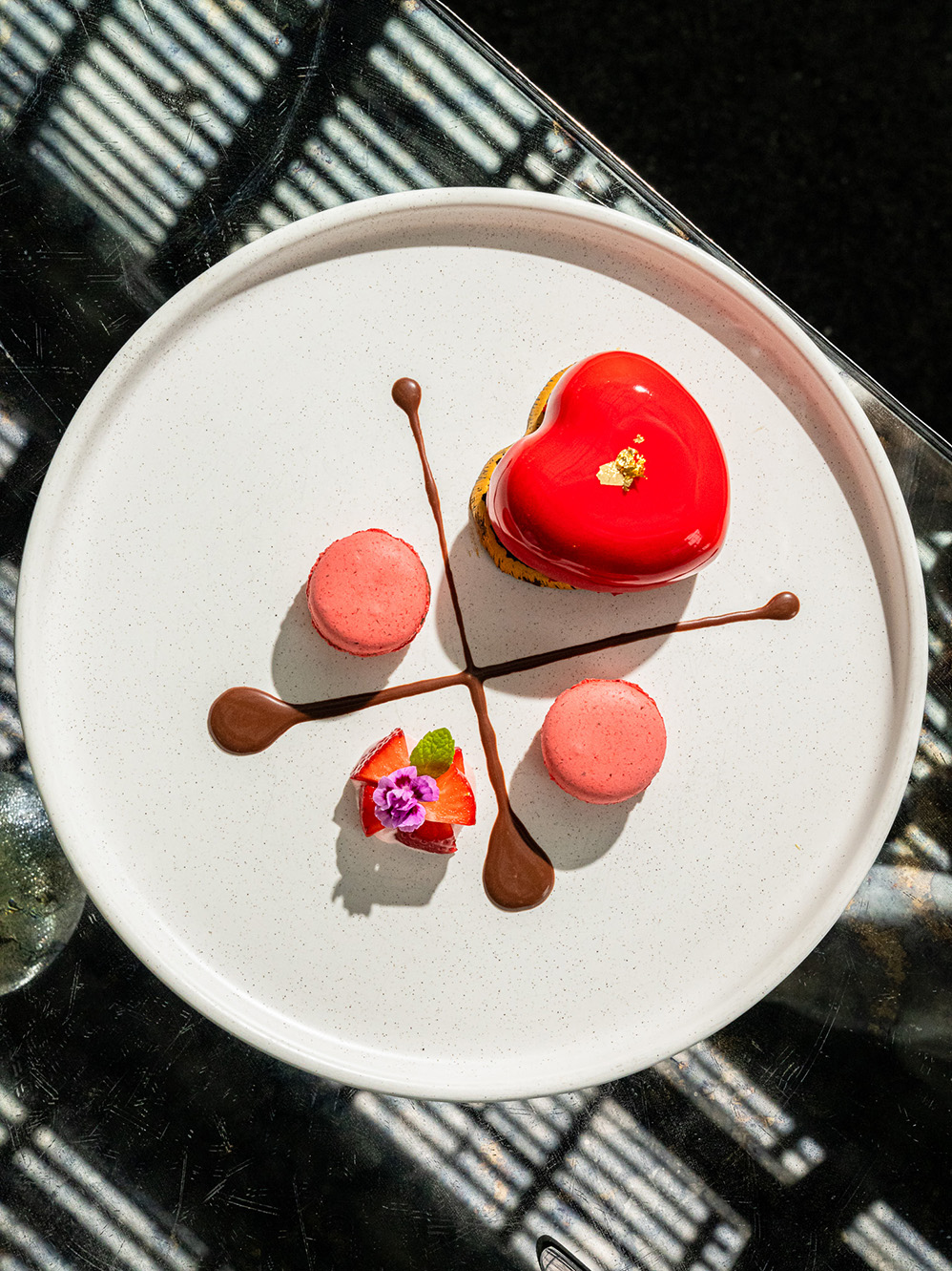 a dish with a macaron strawberries and a little cake with a heart shape