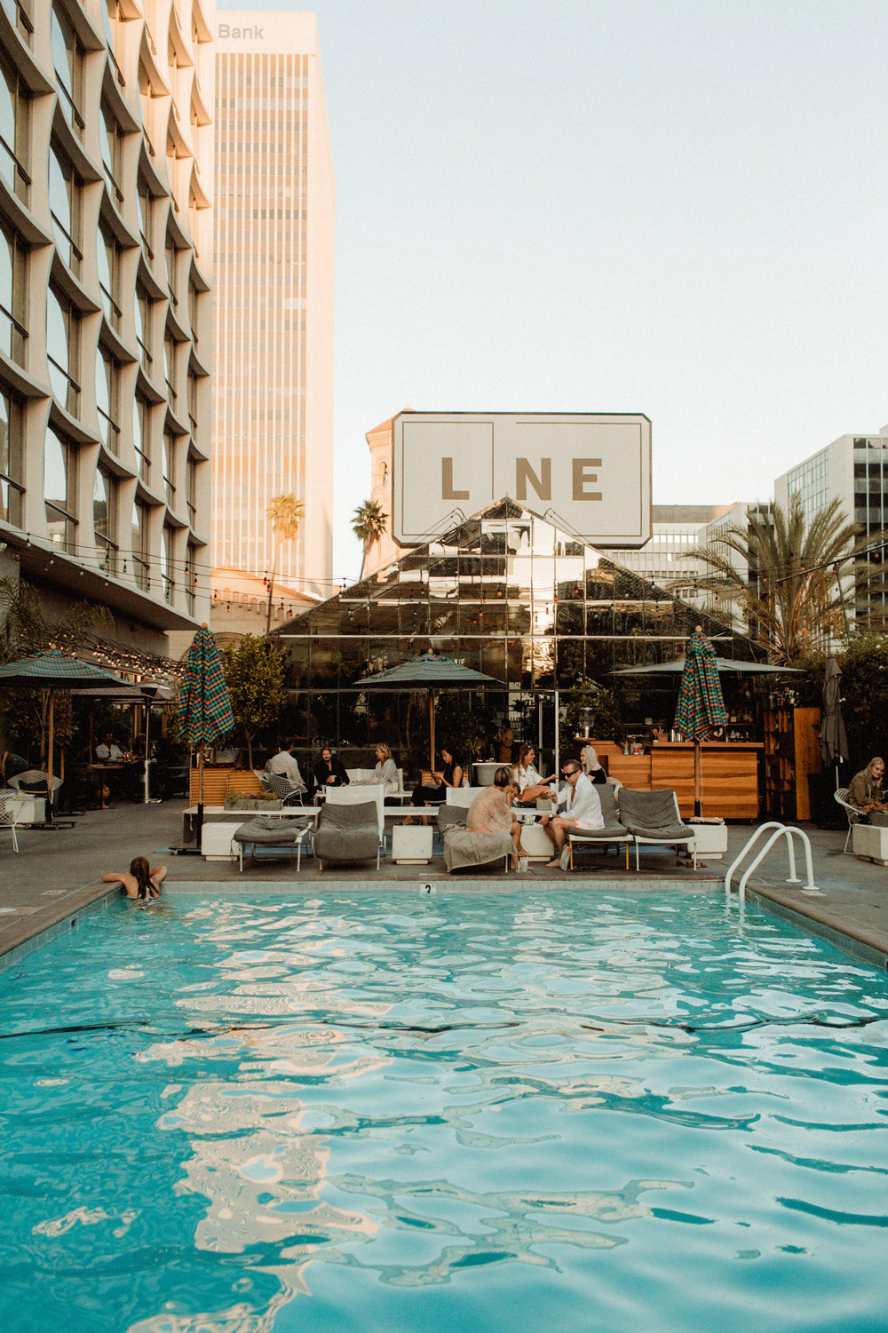 A group of individuals relaxing near the pool area of the line hotel.