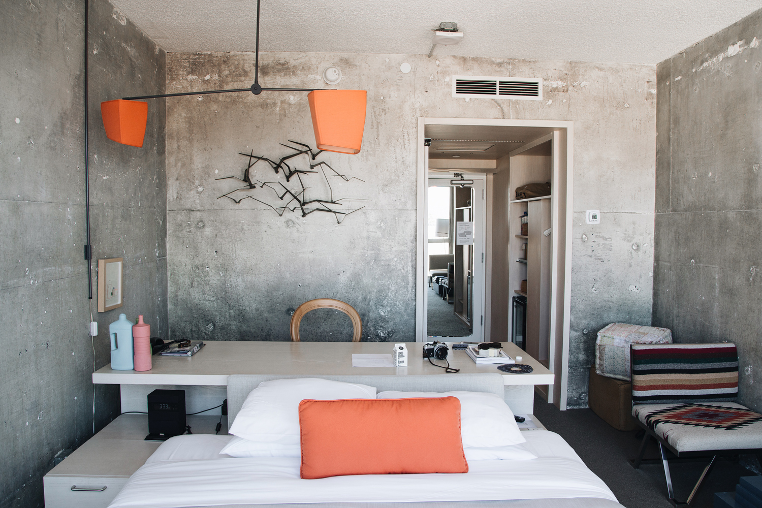 An artistic design adorns the wall just above the long table, accompanied by a chair.