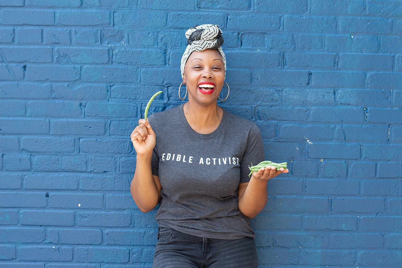 A portrait of Melissa L Jones holding a bunch of vegetable
