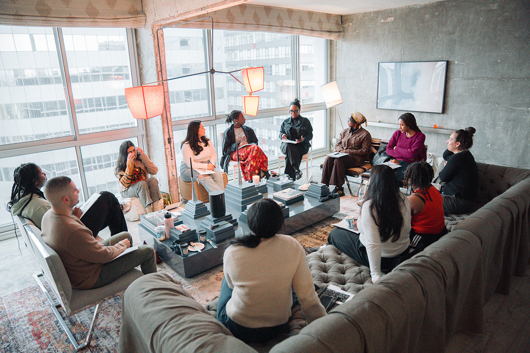 A group of people sitting around in a room talking