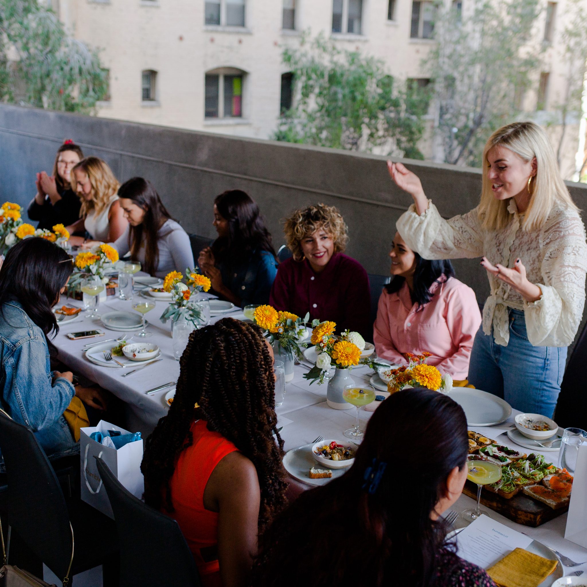 A group of people sitting around a table with food and flowers