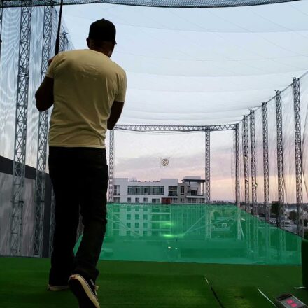 golf player practicing his swing on a golf practice pitch