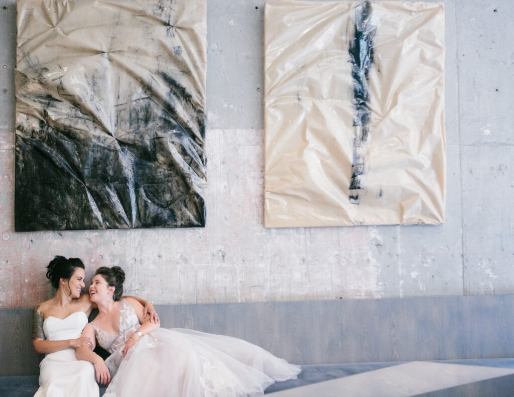 Two woman sitting and posing with the hanging photograph on top