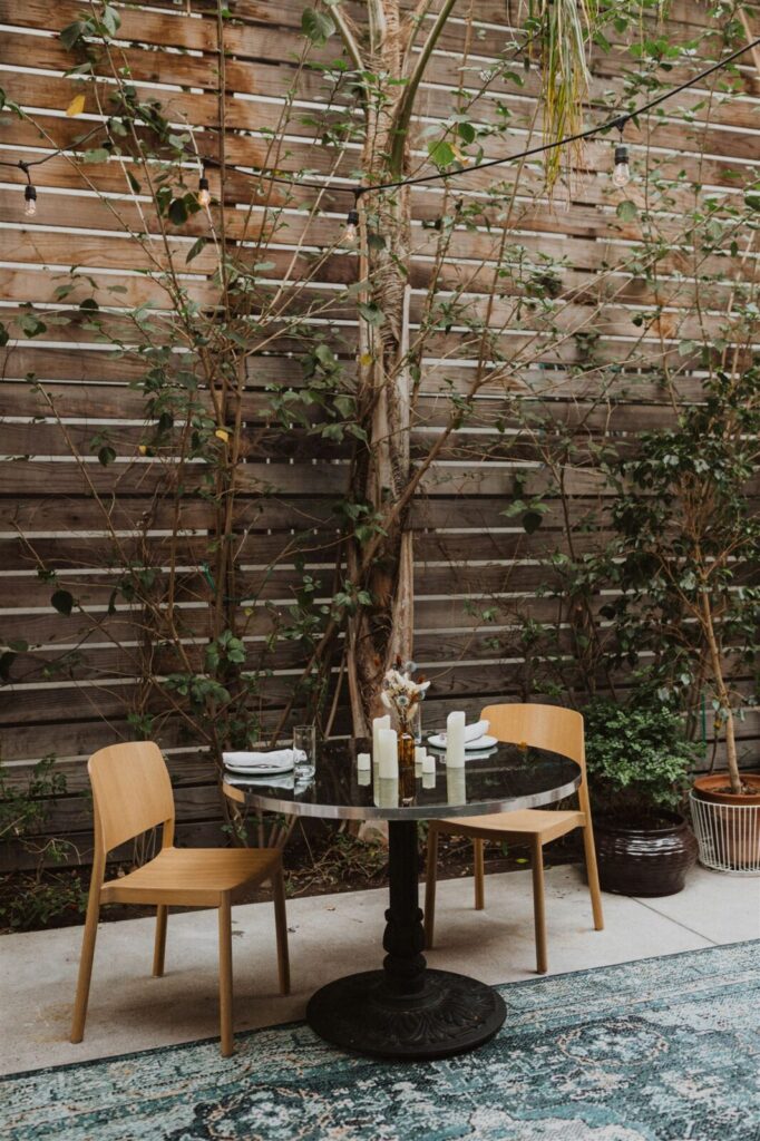 A table with two chairs with wooden background and plants