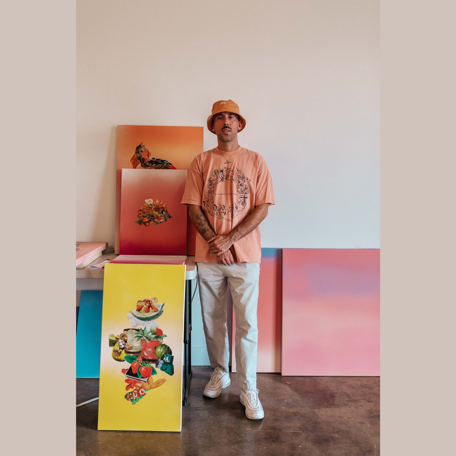 A man stands in front of a group of colorful art canvases
