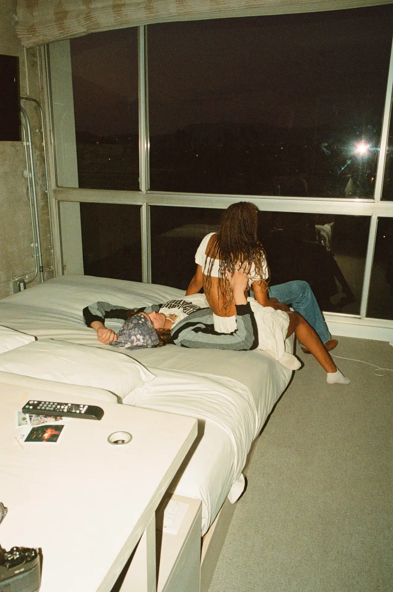 Two people share a quiet moment in a modern bedroom at The LINE, with city lights beyond the window.