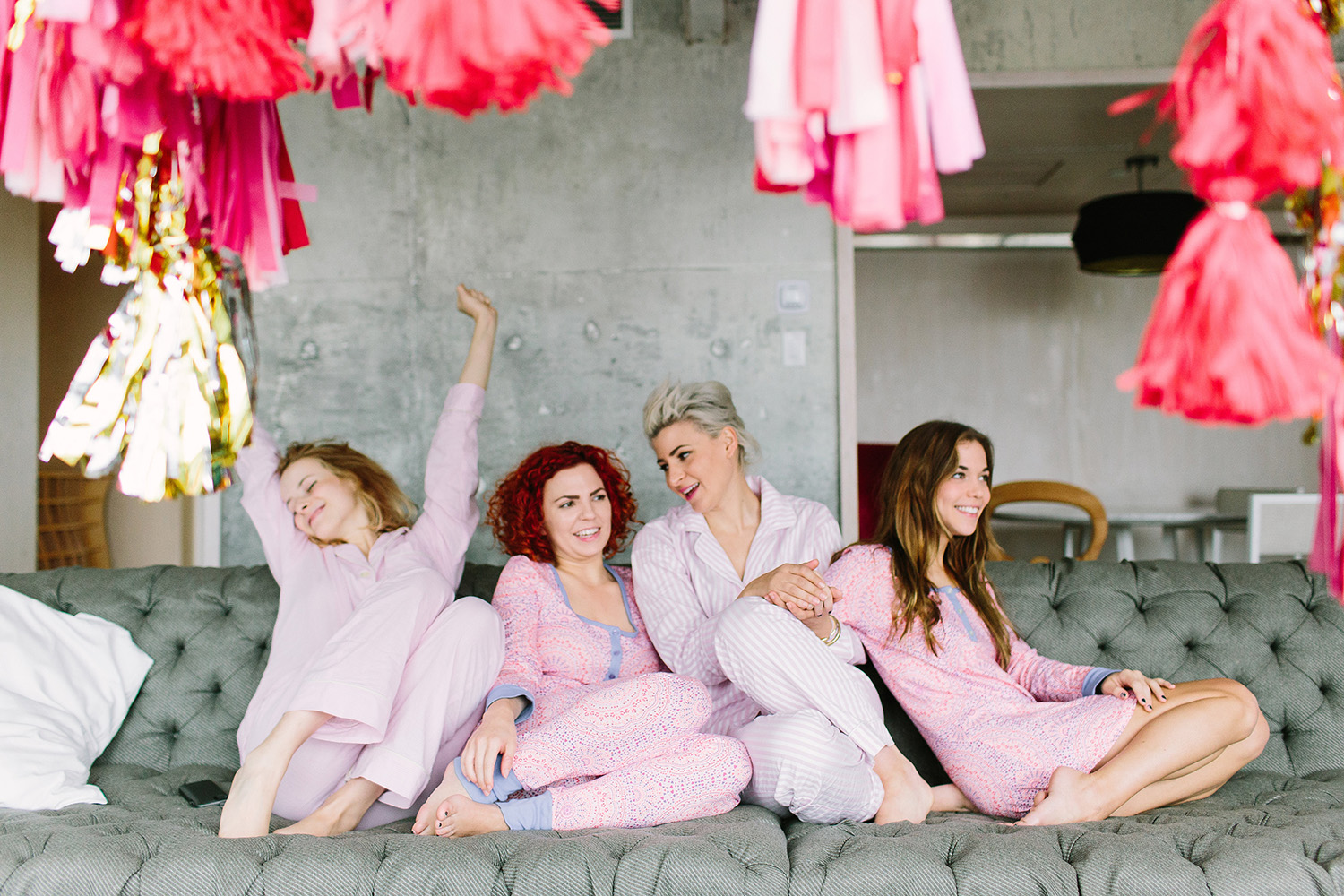 Bachelorette group - A group of people in pink lounging on the couch with pink decoration around the room