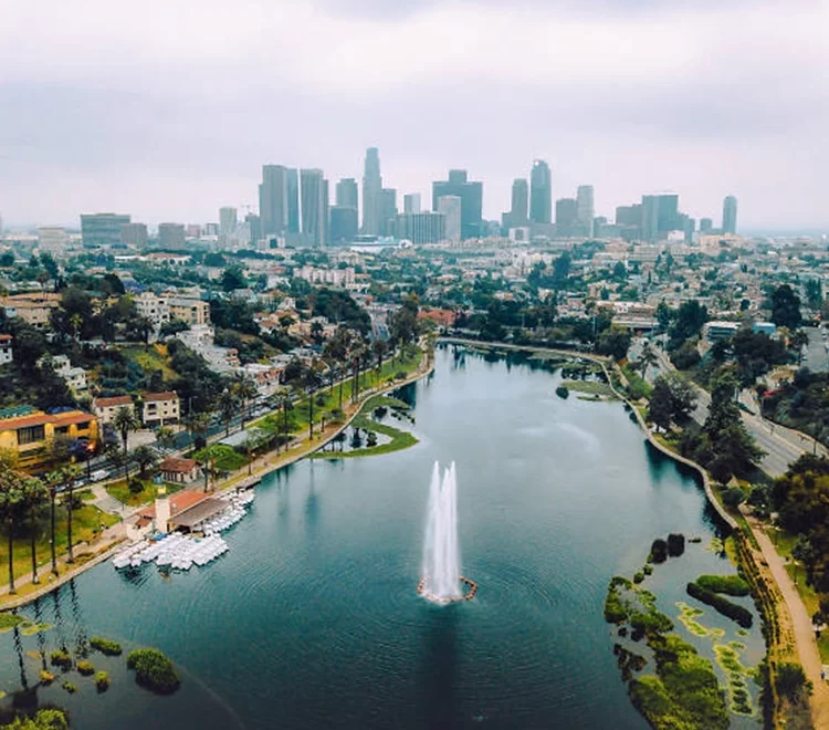 Aerial view of Echo Park Lake with fountain, paddle boats, palm-lined paths, and downtown Los Angeles skyline in background