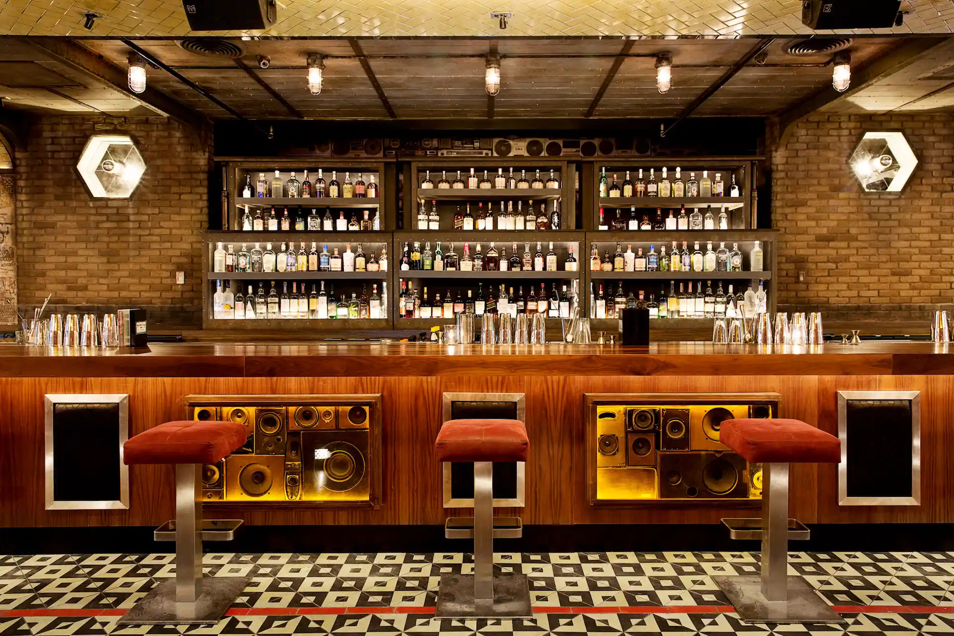 Stylish bar at Break Room 86 with red stools, speaker-front counter, exposed brick walls, and backlit liquor shelves