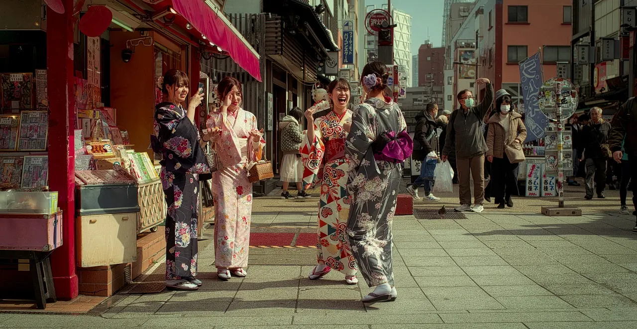 Group in floral kimonos chatting near storefront in Little Tokyo with red awning and busy street