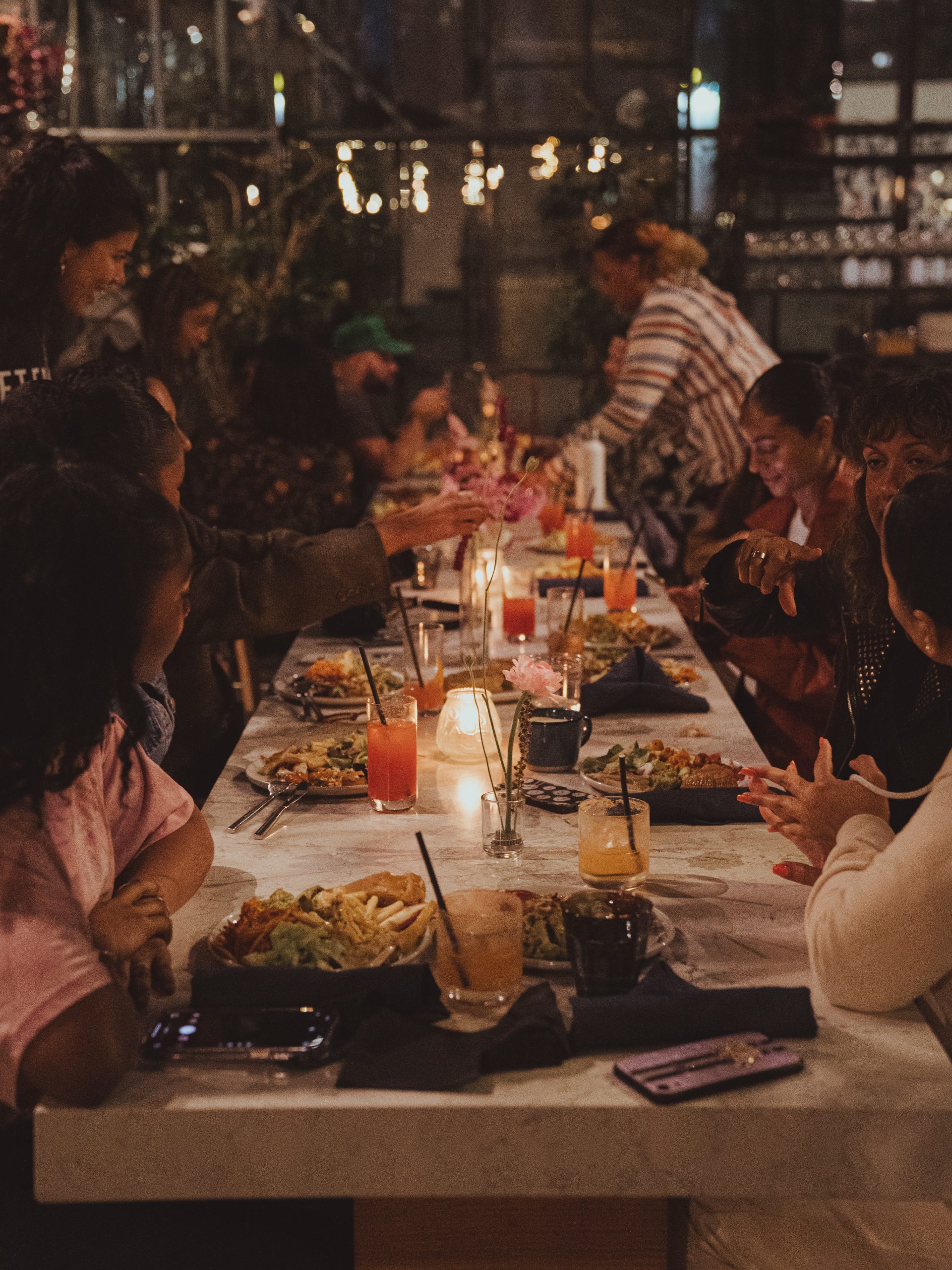 a group of people sitting around a long table with food and drinks