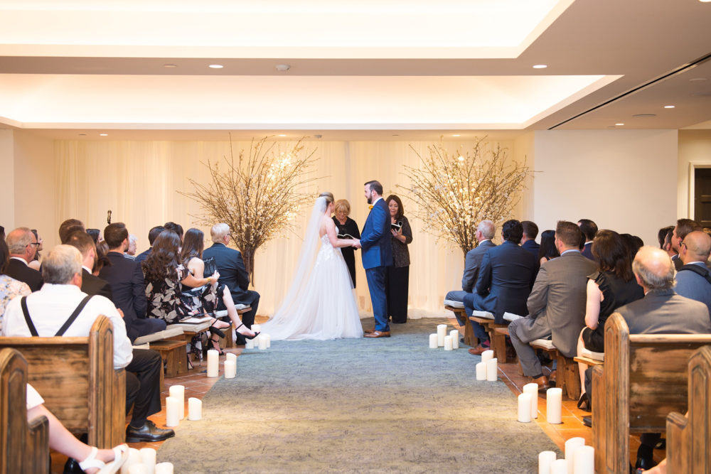 Picture of a couple holding hands to take marriage waos infront of people present in the hall