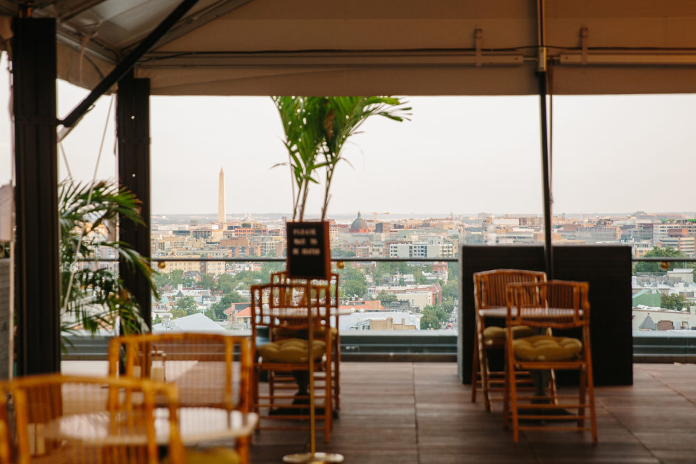 Picture of rooftop with brown chairs and green plants along with city view