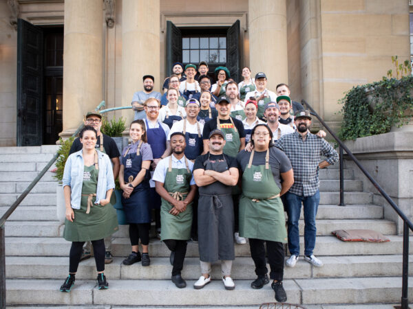 Group picture of chefs standing on the stairs of yellow building