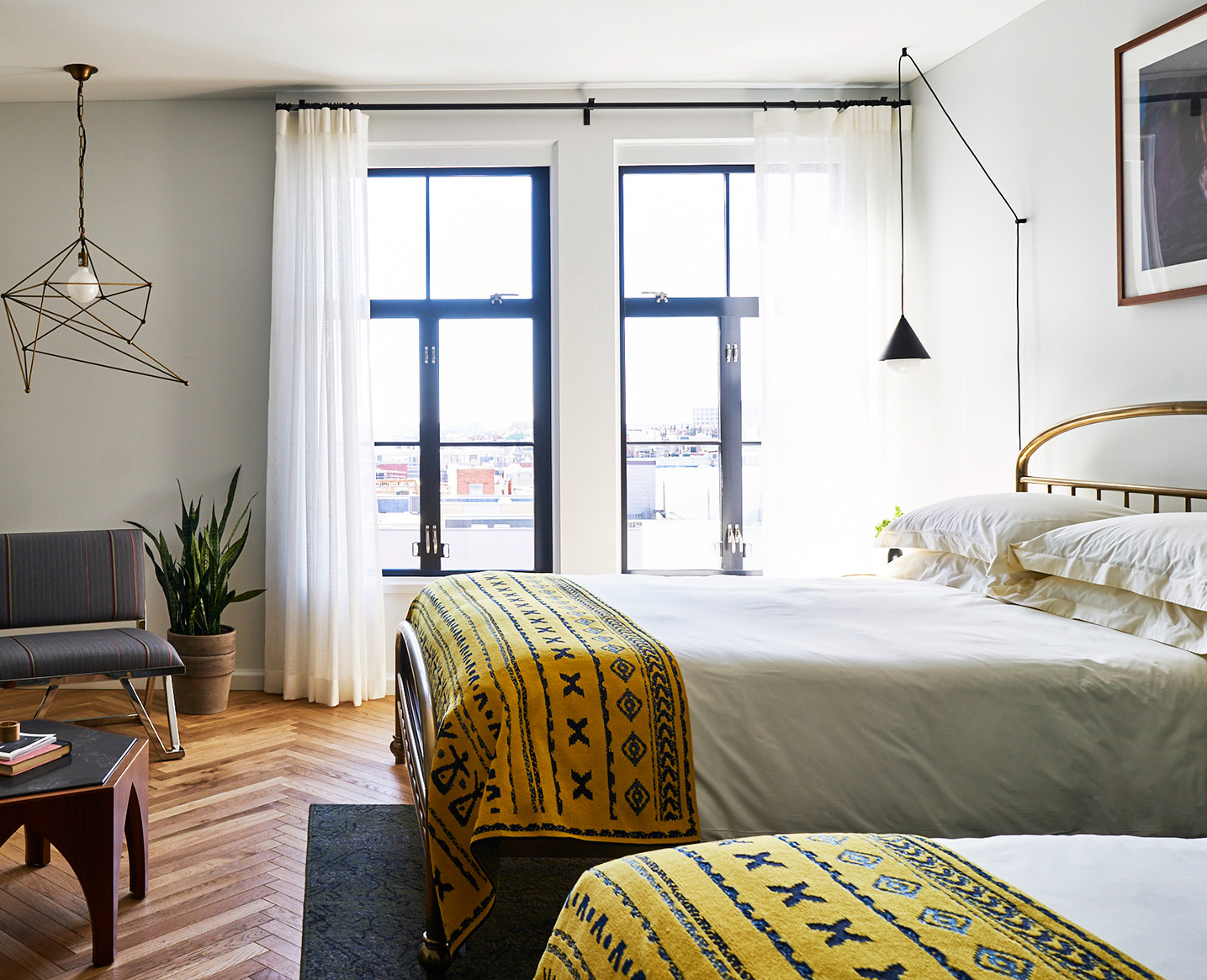 a picture of a bedroom with two beds, large window, and lamp