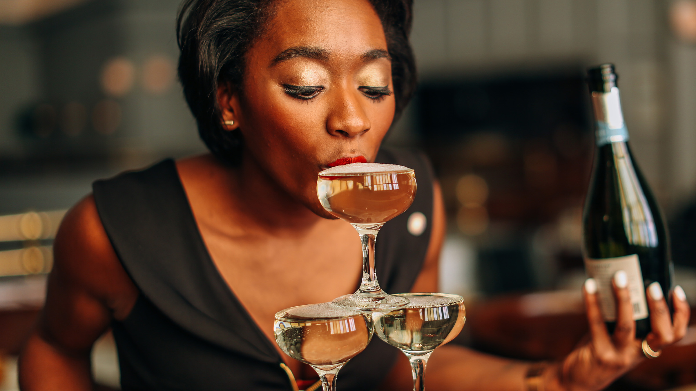 A girl sipping sparkling wine from a tower of glasses