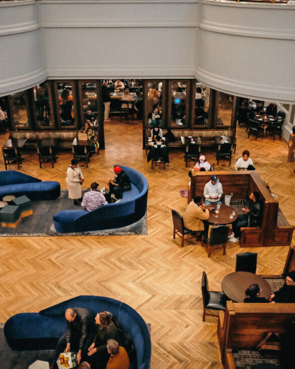 Looking down at a lounge space with blue sofas and wooden table nooks