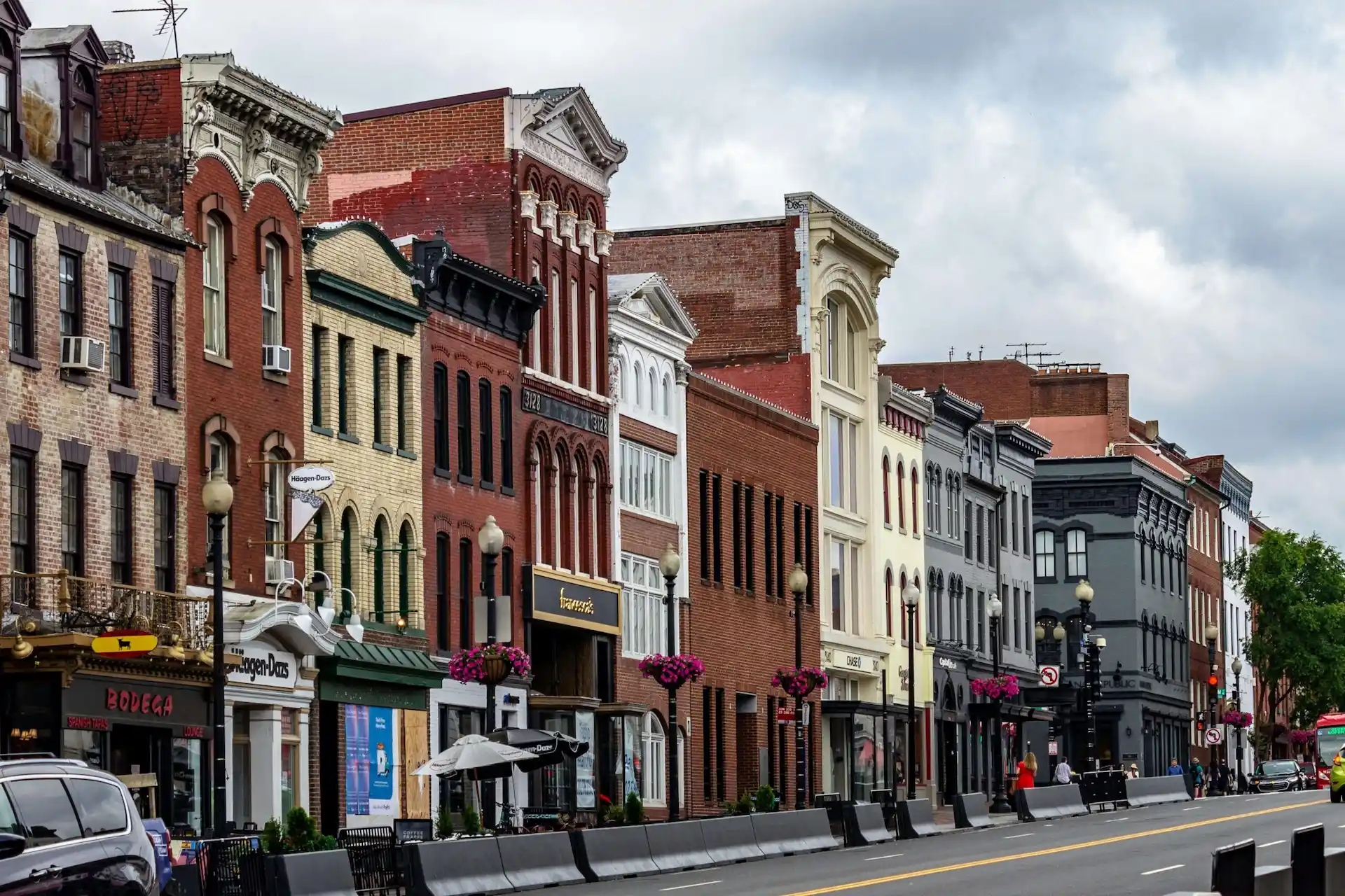 Historic downtown street with brick facades, arched windows, and storefronts like Häagen-Dazs and The Phoenix.