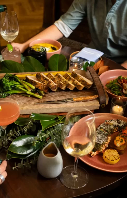 A cozy dinner gathering with friends around a rustic table filled with gourmet dishes, wine glasses, and candles.