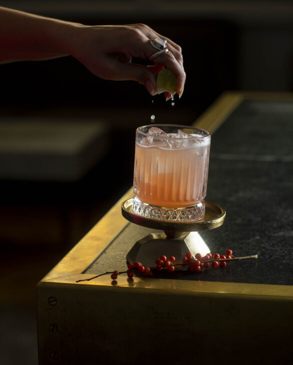 a hand squeezing a lime into a beverage