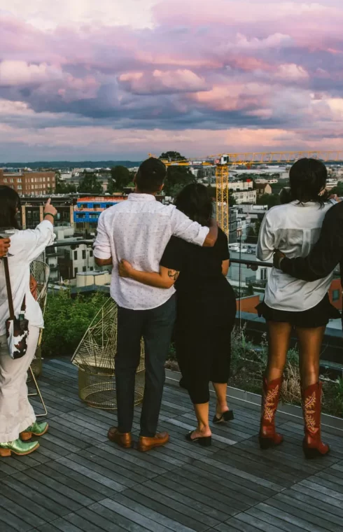 a group of people on the rooftop overlooking the cityscape at twilight