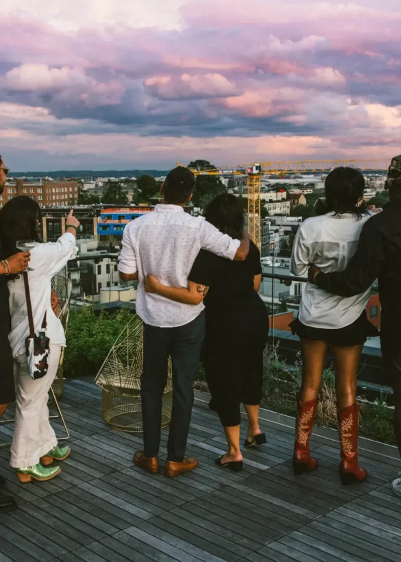 a group of people on the rooftop overlooking the cityscape at twilight