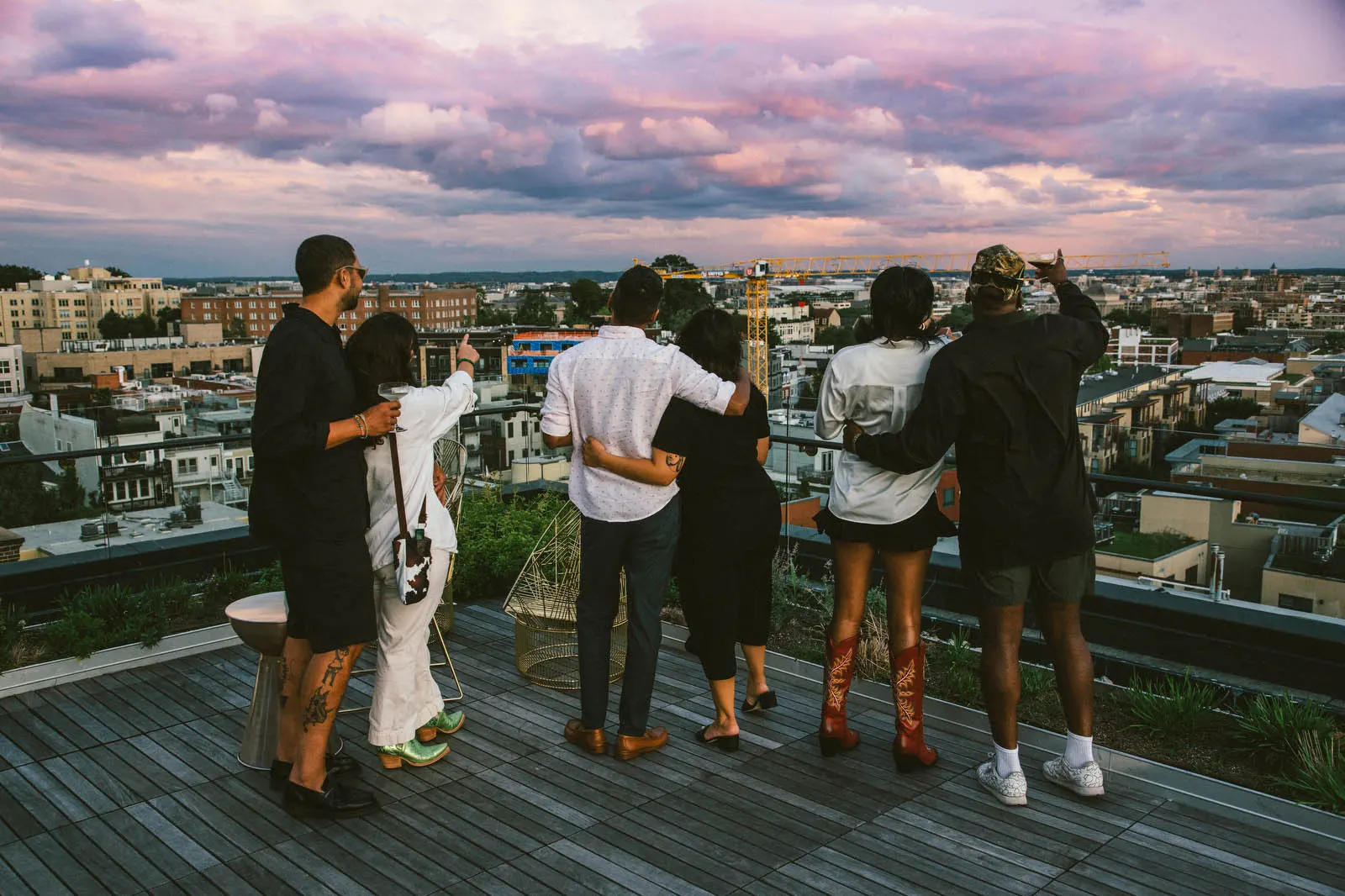 a group of people on the rooftop overlooking the cityscape at twilight