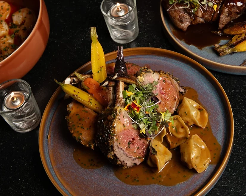 An herb-crusted half rack of lamb paired with luxurious lobster tortellini in red wine lobster jus