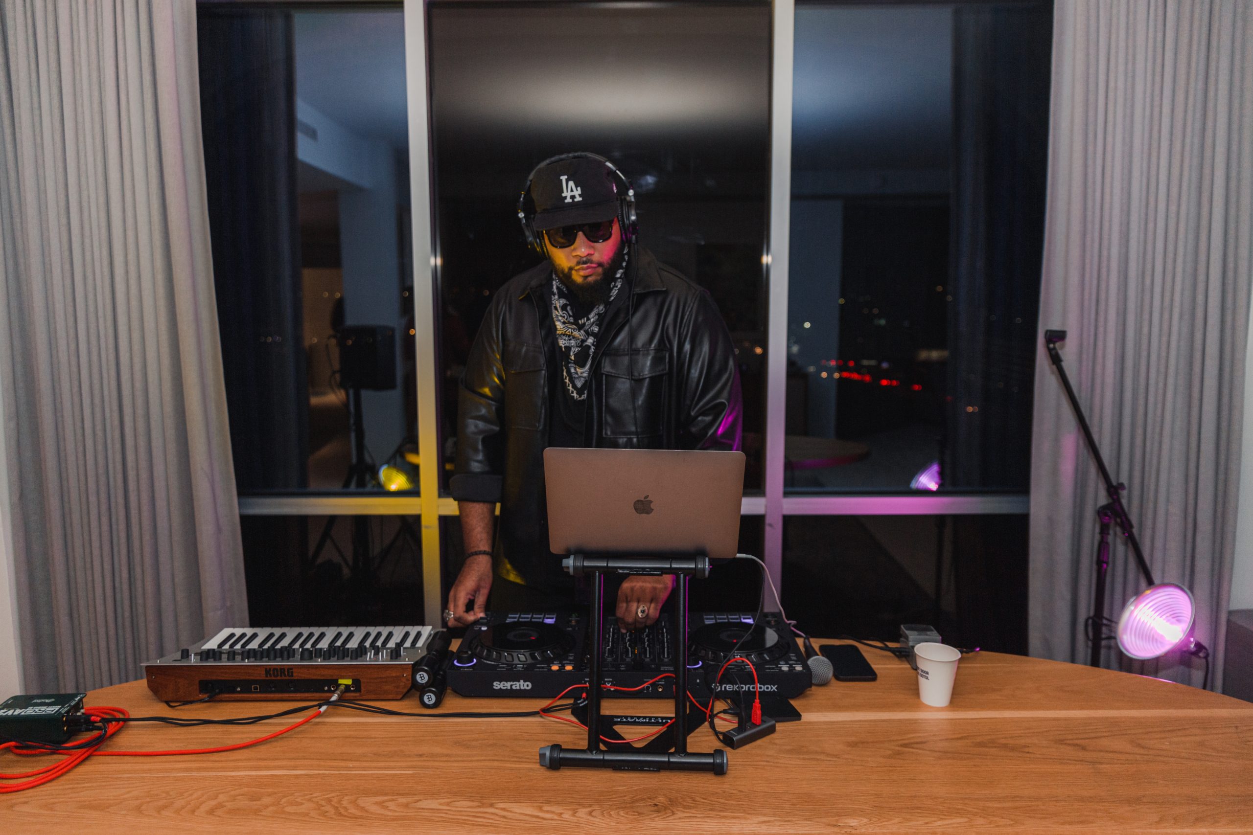 dj playing music with a black cap and sunglasses on a wooden table