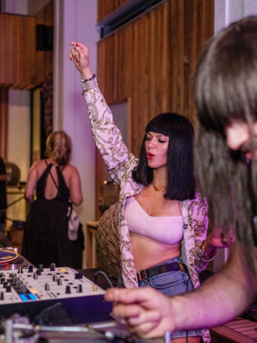 A woman dancing while playing DJ