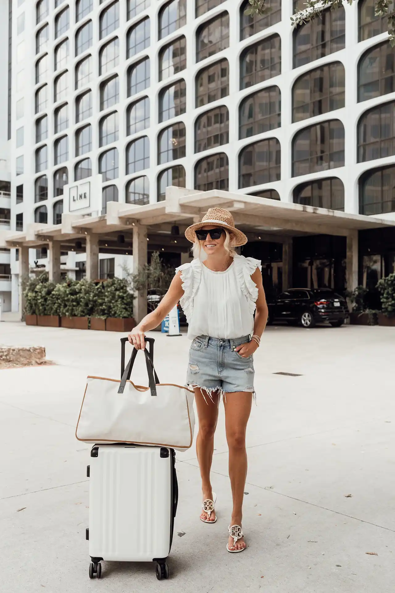 A lady with the luggages in front of the LINE Austin buidling