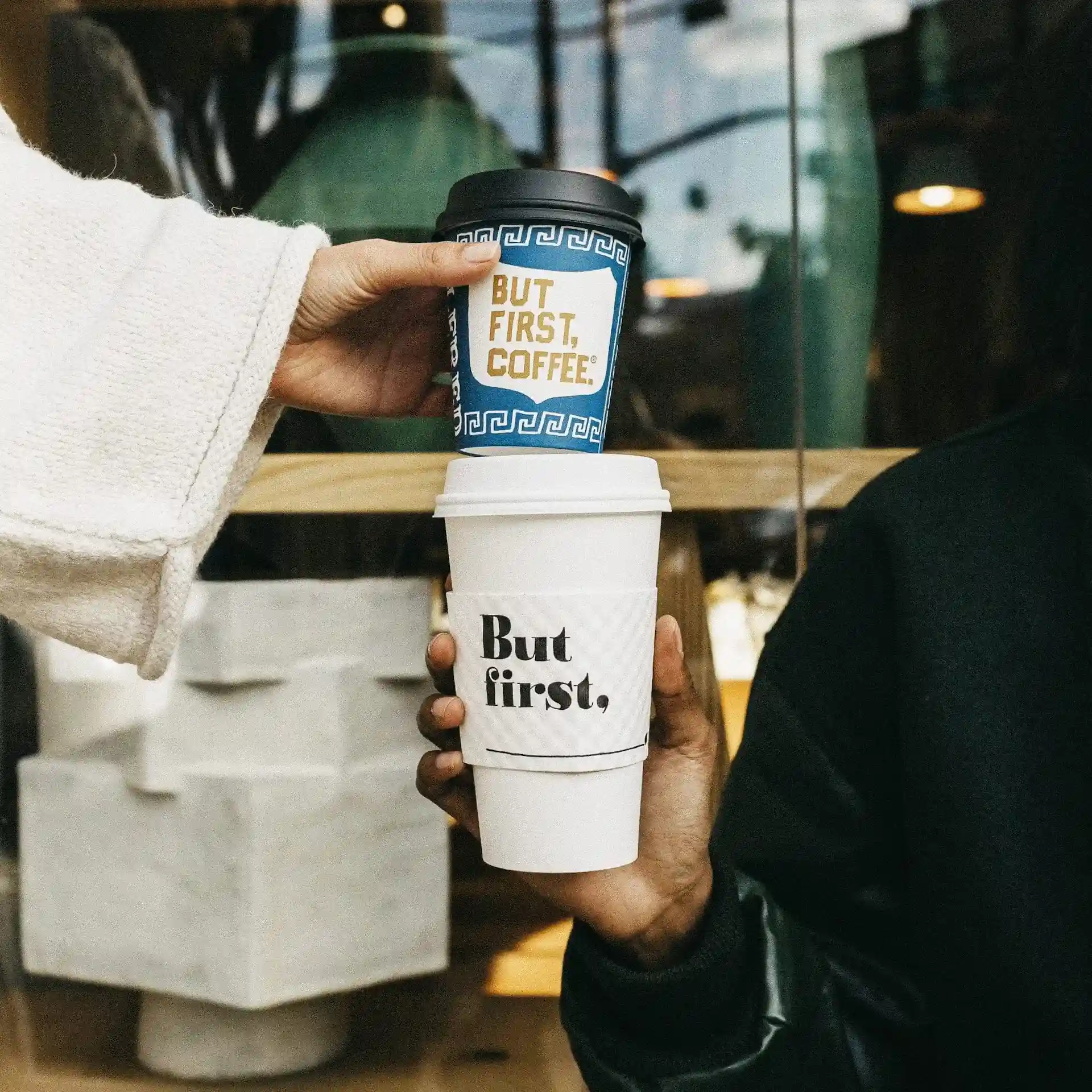 A couple toasting coffee cups while seated at the window, enjoying a scenic view.
